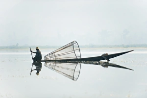 A basket fisherman on Inle Lake scans the still and shallow water for signs of life A basket fisherman on Inle Lake scans the still and shallow water for signs of life