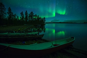 Beached canoes and Aurora Borealis and stars reflected in lake at night, Muonio, Lapland Beached canoes and Aurora Borealis and stars reflected in lake at night, Muonio, Lapland
