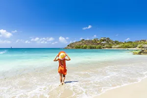 Beautiful woman with orange dress and straw hat standing on a tropical beach, Antigua, West Indies, Caribbean Beautiful woman with orange dress and straw hat standing on a tropical beach, Antigua, West Indies, Caribbean