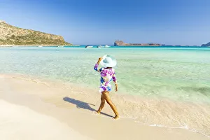 Beautiful woman with sun hat walking on idyllic empty beach, Crete, Greek Islands, Greece Beautiful woman with sun hat walking on idyllic empty beach, Crete, Greek Islands, Greece