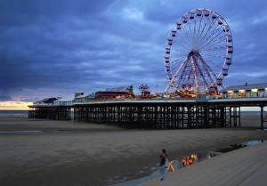 Big wheel and amusements on Central Pier at sunset with young women looking on, Blackpool Big wheel and amusements on Central Pier at sunset with young women looking on, Blackpool