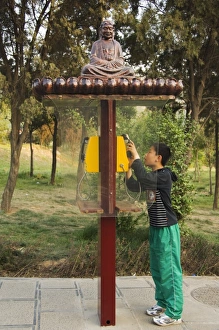 A boy using a monk decorated telephone box at Shaolin temple A boy using a monk decorated telephone box at Shaolin temple