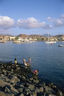Boys on the rocks, with the harbour and town in the background, at Mindelo