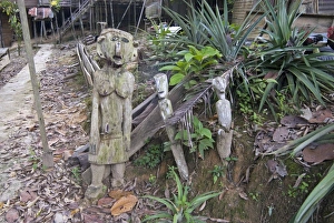 Carved spirits of men and a woman standing at the entrance to Iban tribal longhouse at Ngemah beach on the Lemanak Carved spirits of men and a woman standing at the entrance to Iban tribal longhouse at Ngemah beach on the Lemanak