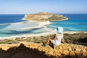 Charming woman with sundress and hat contemplating the crystal turquoise sea and lagoon Charming woman with sundress and hat contemplating the crystal turquoise sea and lagoon