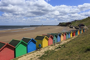 Children kick football near colourful beach huts above West Cliff Beach, Whitby, North Yorkshire Children kick football near colourful beach huts above West Cliff Beach, Whitby, North Yorkshire