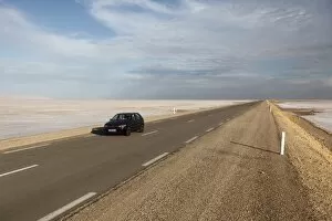 Chott El Jerid, a flat dry salt lake, and automobile on highway between Tozeur and Kebili