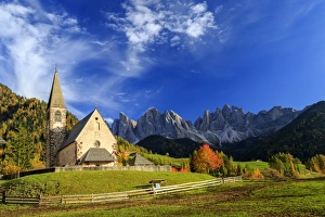 Church of St. Magdalena immersed in the colors of autumn, with the Odle Mountains in the background Church of St. Magdalena immersed in the colors of autumn, with the Odle Mountains in the background