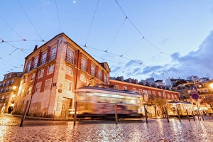 City lights on the typical architecture and old streets at dusk while the tram 28 proceeds City lights on the typical architecture and old streets at dusk while the tram 28 proceeds
