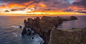 Cliffs by the ocean under the burning sky at dawn, Ponta Do Rosto, Sao Lourenco Peninsula Cliffs by the ocean under the burning sky at dawn, Ponta Do Rosto, Sao Lourenco Peninsula
