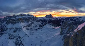 Clouds in the burning sky at sunset over Sassolungo and Sella Group mountains covered Clouds in the burning sky at sunset over Sassolungo and Sella Group mountains covered