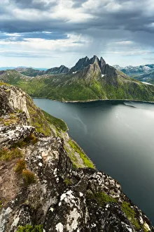 Cloudy sky over the calm water of Mefjord and majestic Breidtinden mountain, Senja island Cloudy sky over the calm water of Mefjord and majestic Breidtinden mountain, Senja island