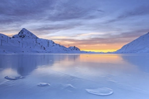 The colors of dawn invading the smooth surface of Lago Bianco exceptionally icy, Bernina Pass, Graubunden, Swiss Alps The colors of dawn invading the smooth surface of Lago Bianco exceptionally icy, Bernina Pass, Graubunden, Swiss Alps