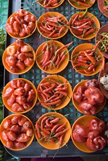 Colourful red chillies and capsicums on orange plates on a market stall in Kuching Colourful red chillies and capsicums on orange plates on a market stall in Kuching