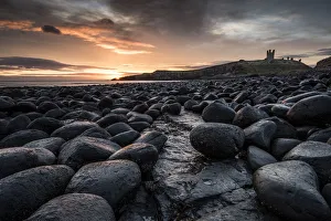 Dawn light reflecting on the rocks at Dunstanburgh Castle on the North East Coast Dawn light reflecting on the rocks at Dunstanburgh Castle on the North East Coast