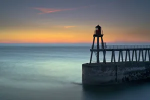 Daybreak over Whitby East Pier and lighthouse, North Yorkshire, England, United Kingdom Daybreak over Whitby East Pier and lighthouse, North Yorkshire, England, United Kingdom