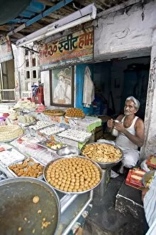 Images Dated 17th October 2009: Diwali sweet stall with stallholder and picture of the Hindu god, Hanuman