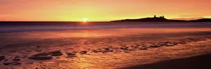 Dunstanburgh castle at sunrise, view across Embleton Bay, Northumberland Dunstanburgh castle at sunrise, view across Embleton Bay, Northumberland
