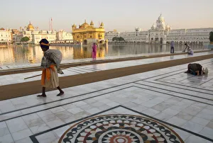 Elderly Sikh pilgrim with bundle and stick walking around holy pool Elderly Sikh pilgrim with bundle and stick walking around holy pool