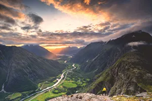 Elevated view of man standing on Romsdalseggen ridge admiring Rauma valley during sunset Elevated view of man standing on Romsdalseggen ridge admiring Rauma valley during sunset