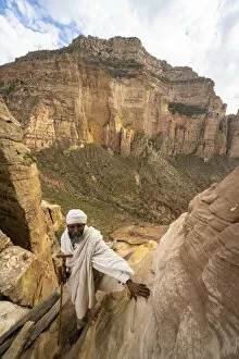 Places Of Worship Gallery: Ethiopian priest leaning on steep rocks leading to Abuna Yemata Guh church