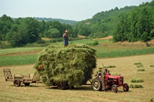 Farming couple with tractor and full trailer during haymaking in a field near Lalbenque Farming couple with tractor and full trailer during haymaking in a field near Lalbenque