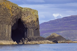 Fingals Cave, the hexagonal mouth of the cave with the heather-covered slopes of Mull behind, Argyll and Bute, Scotland Fingals Cave, the hexagonal mouth of the cave with the heather-covered slopes of Mull behind, Argyll and Bute, Scotland