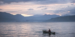 Fisherman in a fishing boat on Lake Toba (Danau Toba) at sunrise, North Sumatra, Indonesia Fisherman in a fishing boat on Lake Toba (Danau Toba) at sunrise, North Sumatra, Indonesia