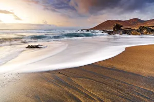 Foam of sea waves on golden sand beach at sunset, Playa de la Solapa, Pajara Foam of sea waves on golden sand beach at sunset, Playa de la Solapa, Pajara