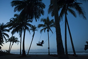 A girl plays on a swing tied between palm trees on the Carribean coast at Palomino in Colombia A girl plays on a swing tied between palm trees on the Carribean coast at Palomino in Colombia