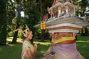 Girl in traditional Thai clothes praying at a spirit house
