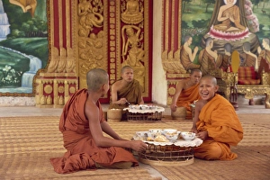A group of Buddhist monks in saffron robes sitting on the floor A group of Buddhist monks in saffron robes sitting on the floor