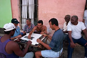 A group of men sitting around a table playing dominoes outdoors, Trinidad A group of men sitting around a table playing dominoes outdoors, Trinidad