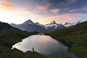 Hiker admiring sunrise from the shores of Bachalpsee lake, Grindelwald, Bernese Oberland Hiker admiring sunrise from the shores of Bachalpsee lake, Grindelwald, Bernese Oberland