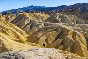 Hiker in the colourful sandstone formations, Zabriskie Point, Death Valley, California, United States of America Hiker in the colourful sandstone formations, Zabriskie Point, Death Valley, California, United States of America