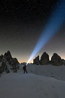 Hiker with head torch admiring stars on Monte Paterno and Tre Cime di Lavaredo Hiker with head torch admiring stars on Monte Paterno and Tre Cime di Lavaredo