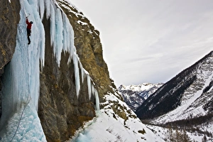 An ice climber ascending a frozen cascade in the Fournel Valley, Ecrins Massif, France An ice climber ascending a frozen cascade in the Fournel Valley, Ecrins Massif, France