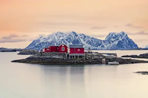 Isolated red fishermen's cabins on rocks in the cold sea at sunset, Svolvaer, Nordland county, Lofoten Islands Isolated red fishermen's cabins on rocks in the cold sea at sunset, Svolvaer, Nordland county, Lofoten Islands