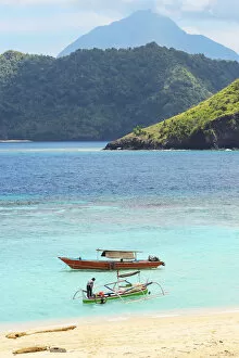 Mahoro Island beach with tour boats and a volcano far beyond on Siau, Mahoro, Siau, Sangihe Archipelago, North Sulawesi