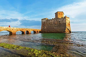 Middle Aged Collection: Man on the bridge walks to the fortified castle of Torre Astura in the water of Tyrrhenian Sea