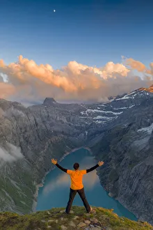 Man with outstretched arms enjoying sunset over lake Limmernsee standing on top of rocks Man with outstretched arms enjoying sunset over lake Limmernsee standing on top of rocks