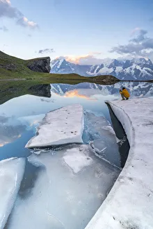 Man photographing Jungfrau mountain from frozen shores of Grauseeli lake at sunset Man photographing Jungfrau mountain from frozen shores of Grauseeli lake at sunset