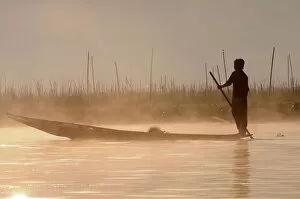 Images Dated 26th December 2007: Man rowing his little rowing boat at sunrise on Inle Lake, Shan States, Myanmar, Asia