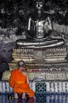 Bangkok Gallery: A monk prays in front of a golden Buddha, Wat Suthat, Bangkok, Thailand, Southeast Asia, Asia