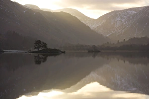 Morning sunlight bursting through clouds over fells with reflections in Lake Ullswater Morning sunlight bursting through clouds over fells with reflections in Lake Ullswater