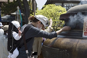 Mother with baby using incense smoke to cure bodily ailments at Zenkoji Temple Mother with baby using incense smoke to cure bodily ailments at Zenkoji Temple