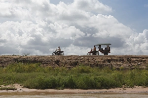 A motorbike being followed by a moto-rickshaw along the banks of the Tonle Sap Lake, Cambodia, Indochina A motorbike being followed by a moto-rickshaw along the banks of the Tonle Sap Lake, Cambodia, Indochina
