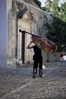 Musician carrying double bass along cobbled street to Plaza Mayor, Trinidad Musician carrying double bass along cobbled street to Plaza Mayor, Trinidad