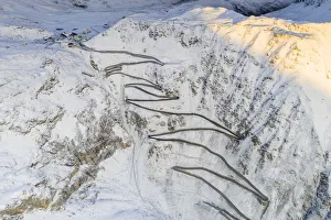 Narrow bends of the Stelvio Pass road on steep snowy mountain ridge, aerial view by drone Narrow bends of the Stelvio Pass road on steep snowy mountain ridge, aerial view by drone