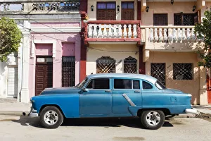 Old blue American car parked in front of old buildings, Cienfuegos Old blue American car parked in front of old buildings, Cienfuegos